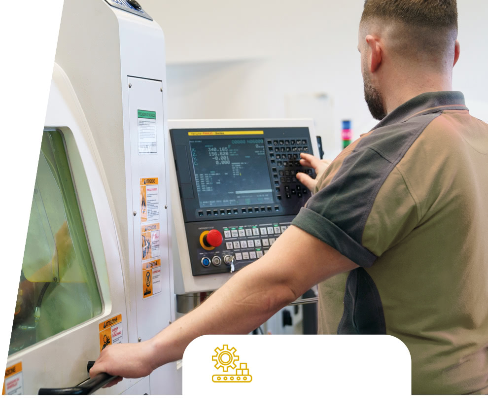 Opérateur Eredi Baitelli à la console de commande d'une machine CNC, à côté du carter de protection.